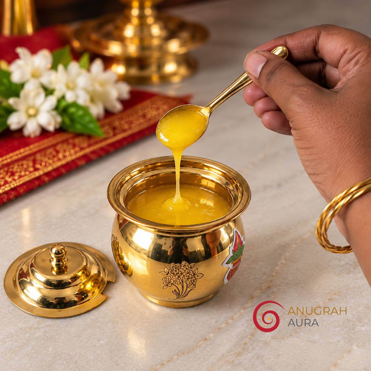 Brass spoon holding golden ghee above an open brass ghee pot